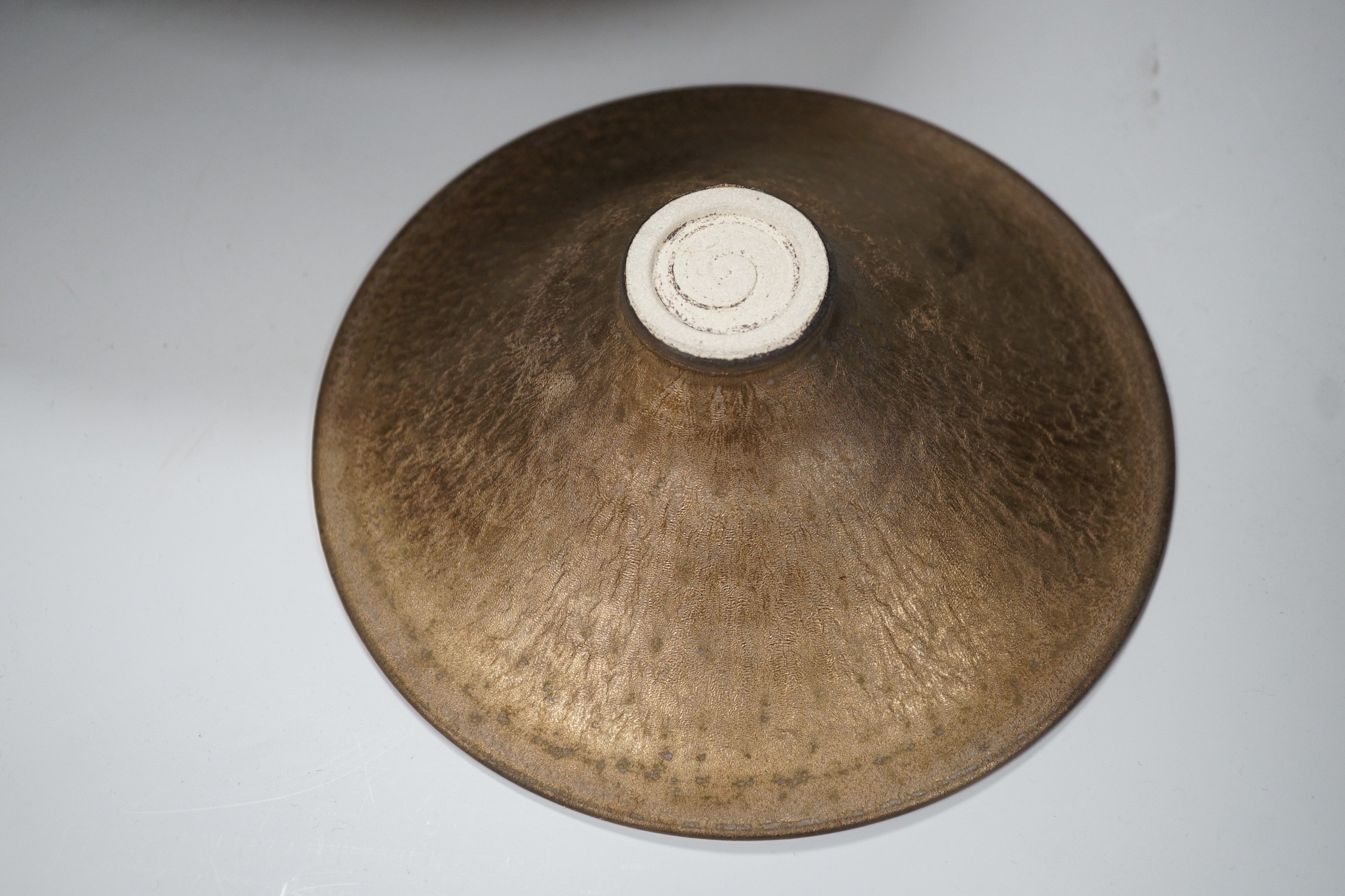 Huw Powell Roberts - two white earthenware open dishes covered in mottled bronze glaze with gold spiral decoration, incised HPR mark, 36.5cms and 19.5cms diameter